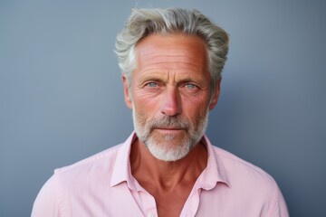Obraz premium A man with a beard and gray hair is wearing a pink shirt