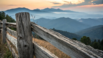 Fototapeta premium Rustic wooden fence overlooking serene mountain landscape at sunset