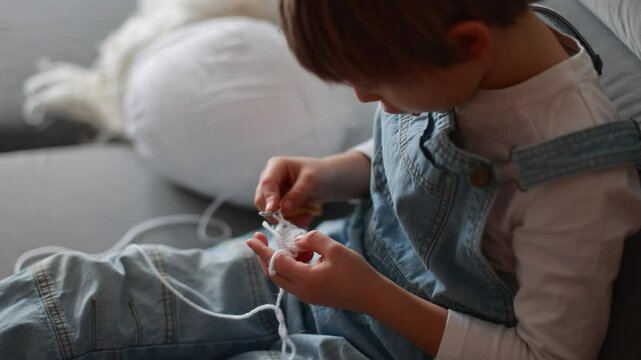 Child, learning crocheting, knitting, hand Crochet basics. Kid sitting at home, crocketing amigurumi figure