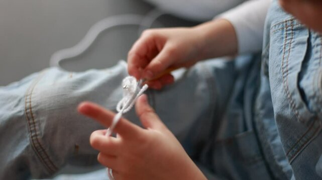 Child, learning crocheting, knitting, hand Crochet basics. Kid sitting at home, crocketing amigurumi figure