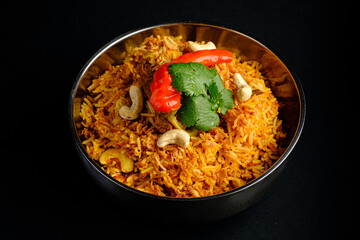 Delicious Biryani Served in a Traditional Metal Bowl Garnished With Fresh Herbs, Cashews, and Vibrant Chilies, All Set Against a Dark Backdrop for an Alluring Culinary Appeal