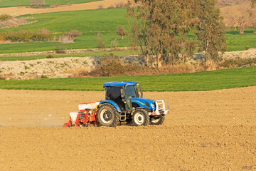 Obraz premium A tractor diligently plants seeds in a crop field, its powerful engine driving the machinery to cultivate the soil and ensure a successful planting season.