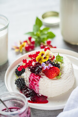 Delicious Berry Dessert Topped With Fresh Fruit and Edible Flowers, Served on a White Plate in a Bright Kitchen