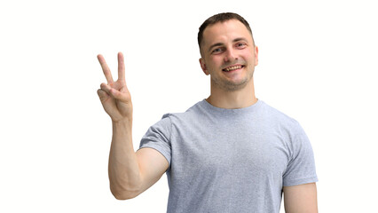 A man in a gray T-shirt, on a white background, close-up, shows a victory sign