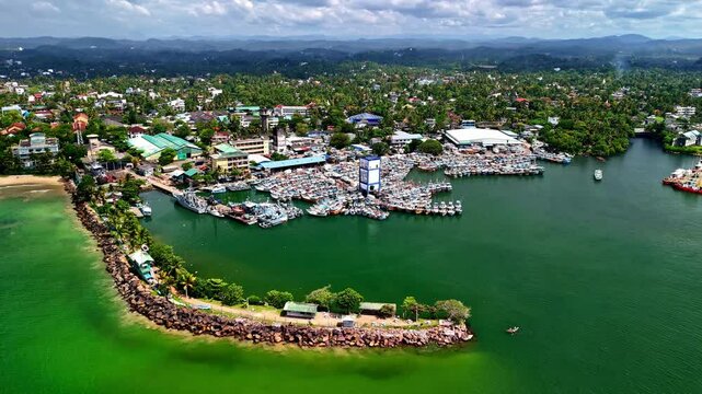 Drone aerial landscape of charter fishing boats docked in wharf jetty pier boardwalk on seaside coastline headland in Galle Sri Lanka Asia transport tourism travel