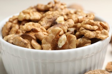 Peeled walnuts in bowl on light table, closeup