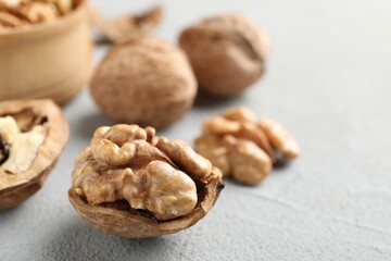 Fresh walnuts with shells on gray table, closeup. Space for text