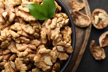 Fresh ripe walnuts in bowl and shells on table, top view