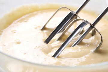 Making dough in bowl with hand mixer, closeup
