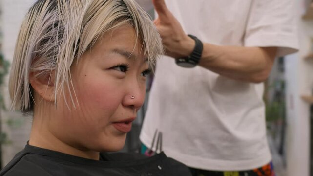 Professional hair stylist working on asian woman client with blonde hair cut