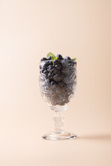 Blueberries in cut glass cup with mint leaves, highlighting textures and details on beige background. Harmonic composition. Copy Space. Concept of healthy eating and natural freshness
