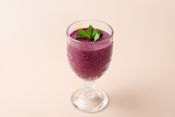 Blueberry smoothie in cut glass cup, garnished with fresh mint on soft background. Copy Space. Elegant and natural styling. Concept of nutrition, freshness and healthy life