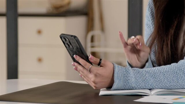 Close-up of deaf-mute teenage girl talking with sign language, communicating with friend online during video call on cellphone indoors.