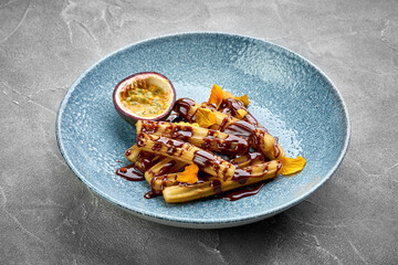 A vibrant and appetizing plate of churros, topped with a rich chocolate sauce and fresh fruit.
