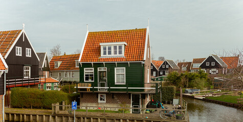 Traditional Dutch House With Orange Roof and Green Wooden Facade Overlooking Tranquil Canal in Charming Village