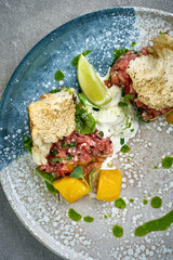 A vibrant and appetizing plate of beef tartare, served with fresh herbs, crispy crackers, and a dollop of creamy sauce