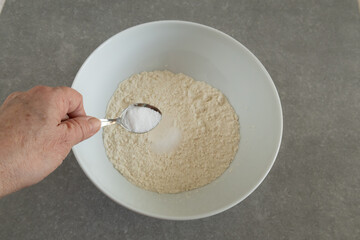 adding salt to flour in a mixing bowl  