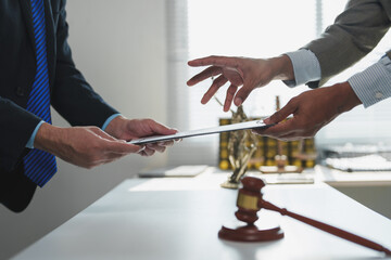 Two lawyers are exchanging legal documents, with a gavel and the scales of justice symbolizing law,...