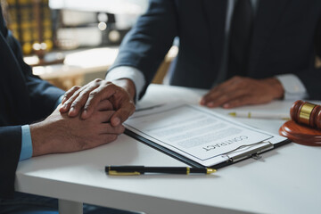 Lawyer is holding client's hands after signing a contract in the office, showing empathy and...