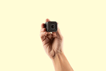 Male hand holding an action camera isolated on yellow background front view