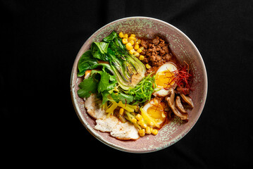 A beautifully arranged bowl of ramen featuring tender slices of meat, soft boiled eggs, fresh...