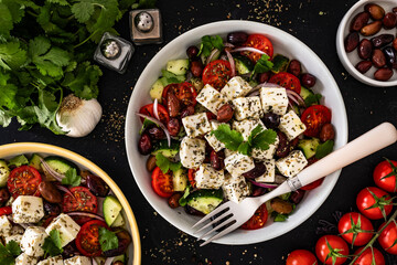 Greek style salad - fresh vegetables with feta cheese, kalamata olives on black table