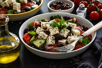 Greek style salad - fresh vegetables with feta cheese, kalamata olives on black table