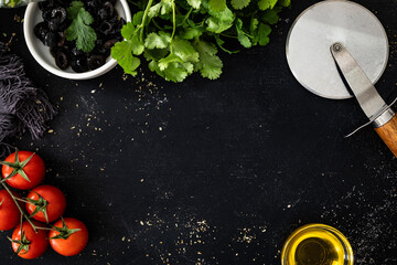 Empty black table with vegetables, pizza cutter and olive oil on side
