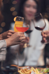 Cheers to Friendship: Close-up shot of friends raising their glasses in a celebratory toast, their hands intertwined, symbolizing camaraderie and joyful moments.