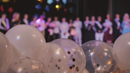 White balloons floating near scattered confetti, blurred graduates celebrating achievement during graduation ceremony © Довидович Михаил