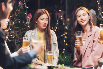 Nighttime Gathering: A group of friends raise their glasses in a lively evening gathering, bathed in the warm glow of string lights.