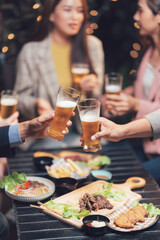Cheers to Friendship: Close-up shot of friends toasting with beer at an outdoor restaurant, surrounded by delicious food.  The image radiates warmth and camaraderie. 