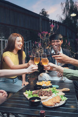 Evening Cheers: Friends raise a toast, celebrating togetherness over a delicious meal and drinks on a patio at dusk.  The warm lighting and laughter create a convivial atmosphere.
