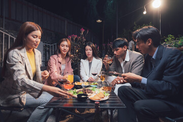 Nighttime Gathering: Friends enjoying a delightful dinner party under the warm glow of outdoor lighting. Laughter, conversation, and shared moments create a sense of camaraderie and connection. 