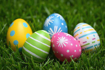 five Easter eggs with distinct colors patterns on green grass