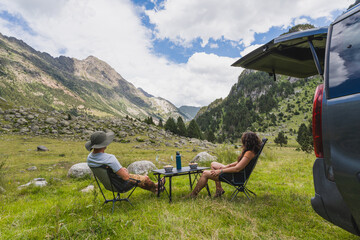 Travelers relaxing by their camper van in the Pyrenees, surrounded by nature. Concept of van life, outdoor adventure, and summer travel.