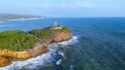 Aerial Drone view of the beach with white sand, coral rocks, hills with trees, waves from the ocean which is a tourist destination known as Krakal Beach Gunung Kidul Yogyakarta