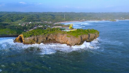 Aerial Drone view of the beach with white sand, coral rocks, hills with trees, waves from the ocean which is a tourist destination known as Krakal Beach Gunung Kidul Yogyakarta