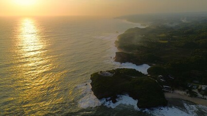 Bird eye view Sunset on the edge of the ocean bordering coral hills with waves from the sea at Krakal Beach, Gunung Kidul, Yogyakarta