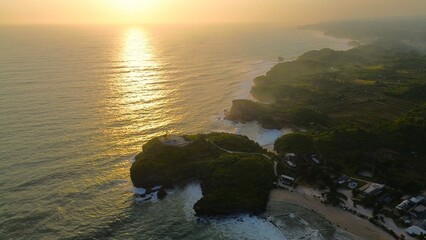 Bird eye view Sunset on the edge of the ocean bordering coral hills with waves from the sea at Krakal Beach, Gunung Kidul, Yogyakarta