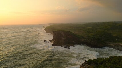 Bird eye view Sunset on the edge of the ocean bordering coral hills with waves from the sea at Krakal Beach, Gunung Kidul, Yogyakarta
