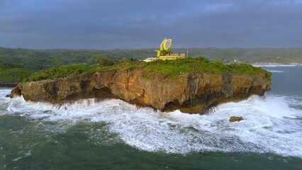 Aerial Drone view of the beach with white sand, coral rocks, hills with trees, waves from the ocean which is a tourist destination known as Krakal Beach Gunung Kidul Yogyakarta