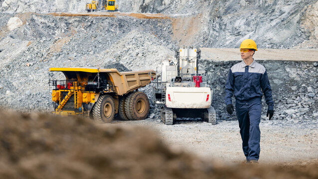 Engineer worker work in open pit mine with mining truck in background