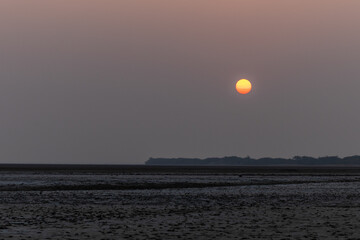 sun rising over farm fields with bright orange sky at morning