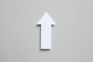 Paper arrow on gray background, top view