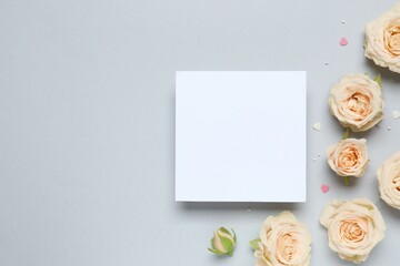 Beautiful composition with peony roses and white paper card on gray background