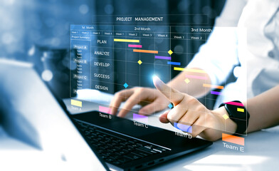 Project manager working on laptop and updating tasks and milestones progress planning with Gantt chart scheduling interface for company on virtual screen.  Business Project Management System. 