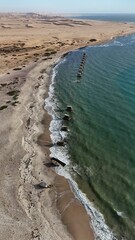  Calm green ocean with cement pillars along Beach and dunes in