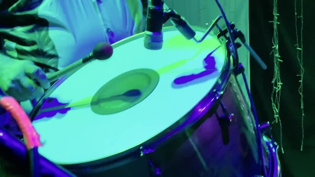4K extreme close-up of a zabumba player striking the drum with precision during a forr&oacute; performance. The warm glow of stage lights enhances the rhythmic energy of this traditional Brazilian party scen