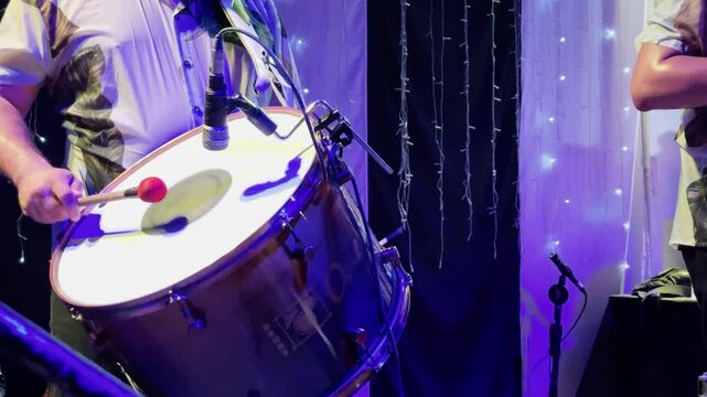 4K close-up of a zabumba player performing forr&oacute; at a lively party. The rhythmic drumbeats, combined with warm stage lights, capture the essence of Brazilian folk music and cultural celebration.